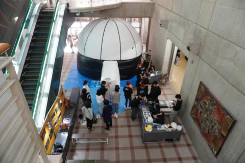 Visitors gathering beside an inflatable planetarium in an indoor hall