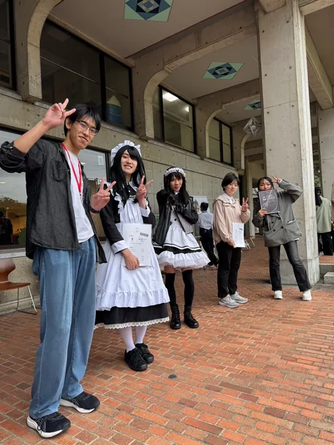 A group of students welcoming visitors outside a cafe