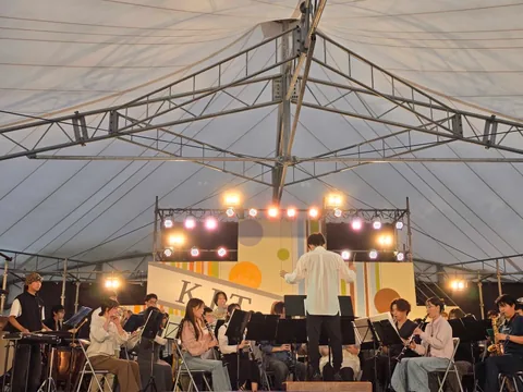 A concert band performing under the stage tent