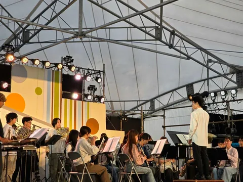 A side view of a concert band and conductor performing