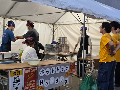 Students preparing food at a hot dog stall
