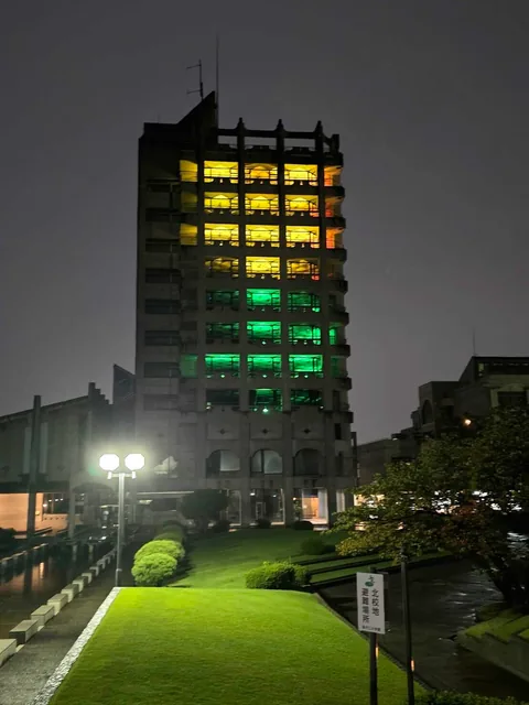 The campus tower illuminated in yellow and green at night
