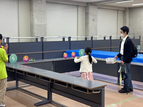 A child playing a target toss game at an indoor festival activity